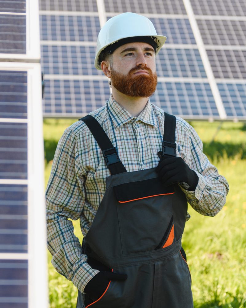 Technician wearing safety gear works on solar panel installation, promoting sustainable energy solutions in a sunny outdoor environment